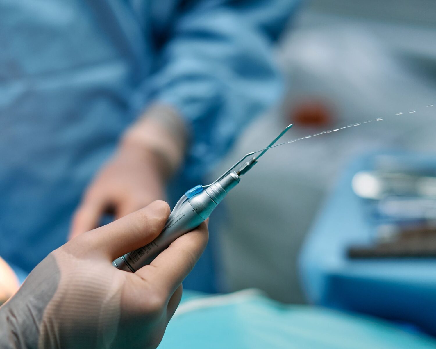 A surgeon's gloved hands holding a precision surgical instrument